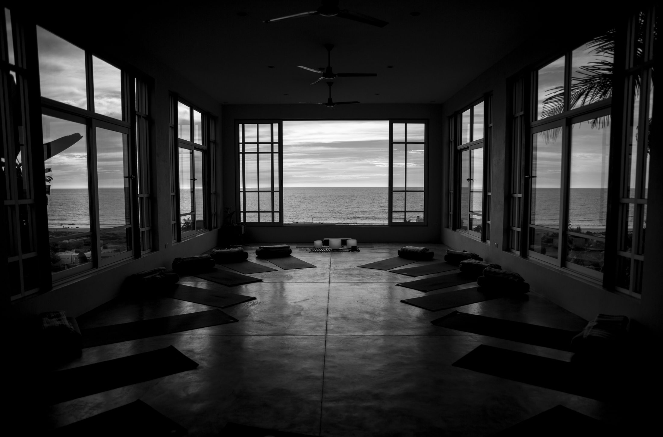 An oceanfront studio at dusk, mats laid out facing the water.
